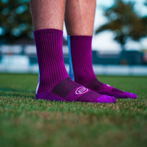 Zijaanzicht van paarse voetbalsokken met gripnoppen op grasveld.